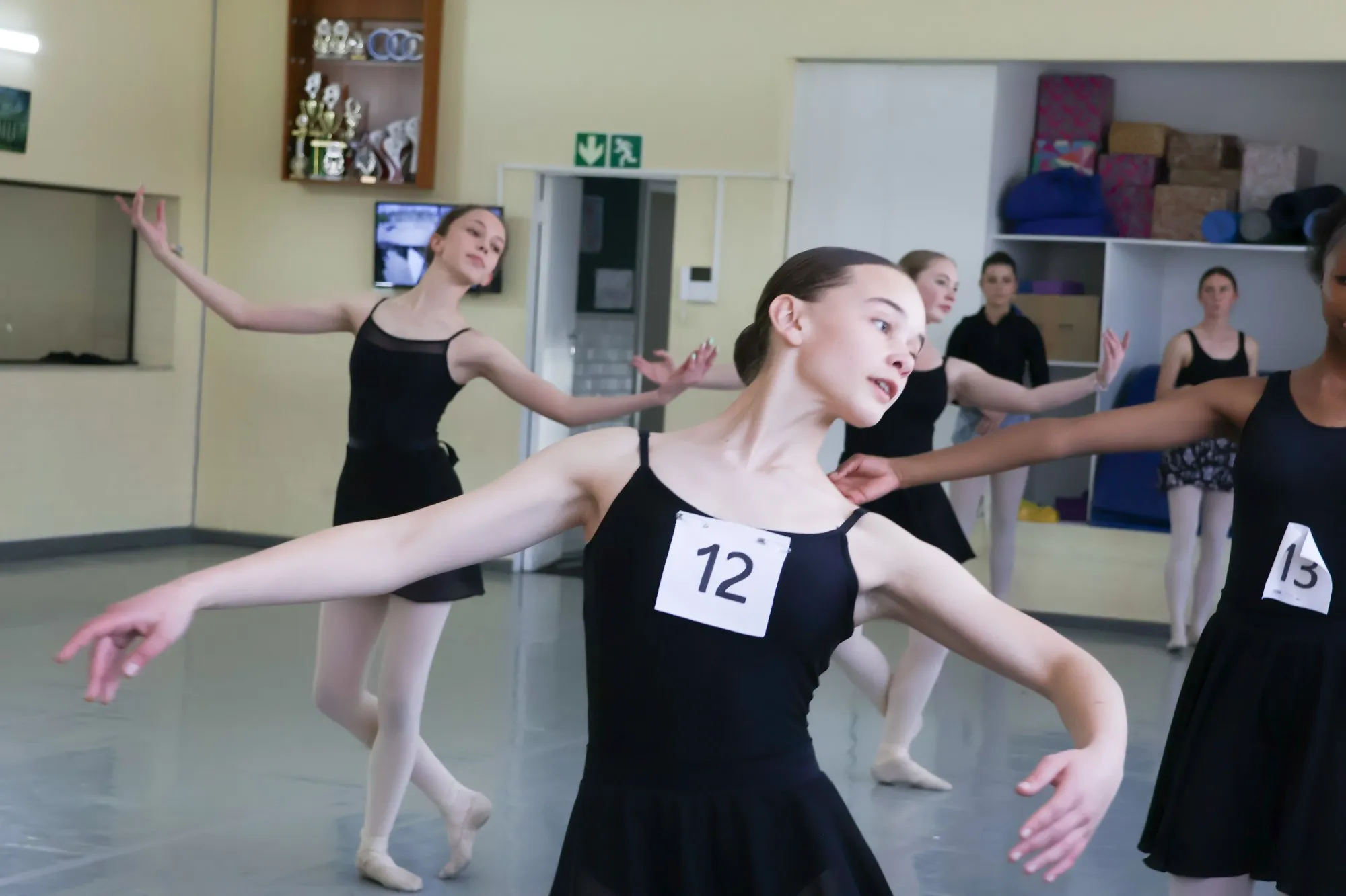 A dancer at a YRBC audition holding her arms out in a ballet pose, in the background there are several other girls also taking part in the audition.